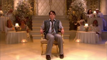 Movie still from “Reefer Madness: The Movie Musical” (2005), directed by Andy Fickman – A man sitting on a chair in a room; Wide shot, High angle