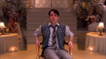 Movie still from “Reefer Madness: The Movie Musical” (2005), directed by Andy Fickman – A man sitting in a chair wearing a vest and a tie; Medium shot, High angle