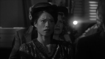 Movie still from “Reefer Madness: The Movie Musical” (2005), directed by Andy Fickman – A black and white photo of a woman wearing a hat; Close Up shot, Over the shoulder angle