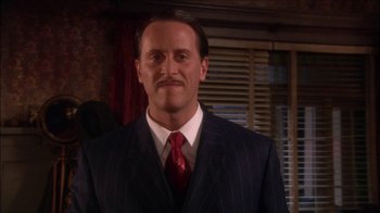 Movie still from “Reefer Madness: The Movie Musical” (2005), directed by Andy Fickman – A man in a suit and red neck tie; Close Up shot, Over the shoulder angle