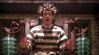 Movie still from “Reefer Madness: The Movie Musical” (2005), directed by Andy Fickman – A man in a jail cell wearing a crown of bells on top of his head; Medium shot, High angle