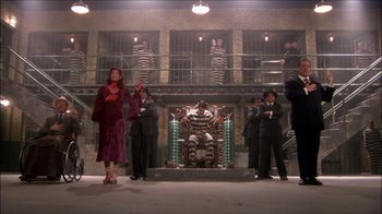Movie still from “Reefer Madness: The Movie Musical” (2005), directed by Andy Fickman – A group of men and women standing in front of a jail cell; Wide shot, High angle
