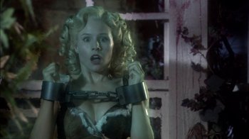 Movie still from “Reefer Madness: The Movie Musical” (2005), directed by Andy Fickman – A woman chained up to a wall with her hands on her chest; Close Up shot, Over the shoulder angle