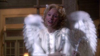 Movie still from “Reefer Madness: The Movie Musical” (2005), directed by Andy Fickman – A woman dressed as an angel holding a cross; Medium shot, High angle