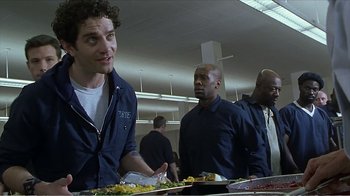 Movie still from “Reindeer Games” (2000), directed by John Frankenheimer – A group of men standing around a table with plates of food on it; Medium shot, Over the shoulder angle