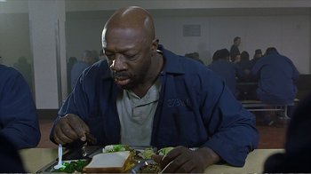 Movie still from “Reindeer Games” (2000), directed by John Frankenheimer – A man sitting at a table with a sandwich in front of him; Medium shot, High angle