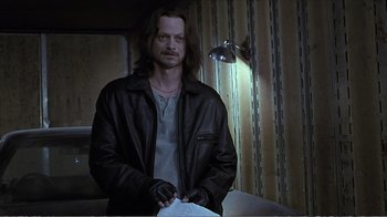 Movie still from “Reindeer Games” (2000), directed by John Frankenheimer – A man in a leather jacket standing in front of a lamp; Medium shot, Low angle