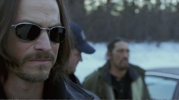 Movie still from “Reindeer Games” (2000), directed by John Frankenheimer – A man with long hair wearing sunglasses and a baseball cap; Close Up shot, Over the shoulder angle