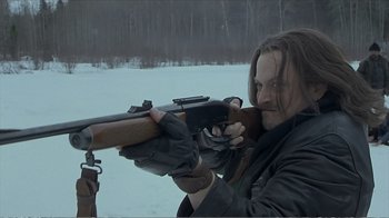Movie still from “Reindeer Games” (2000), directed by John Frankenheimer – A man holding a rifle while standing in the snow; Close Up shot, Over the shoulder angle