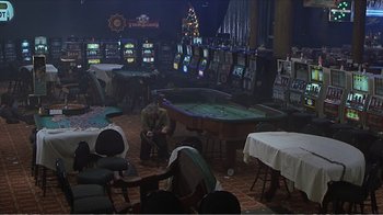 Movie still from “Reindeer Games” (2000), directed by John Frankenheimer – A man sitting at a table in front of a television; Extreme Wide shot, High angle