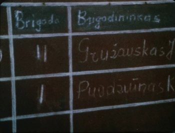 Movie still from “Reminiscences of a Journey to Lithuania” (1972), directed by Jonas Mekas – A chalkboard that has some writing on it on it; Extreme Close Up shot, High angle