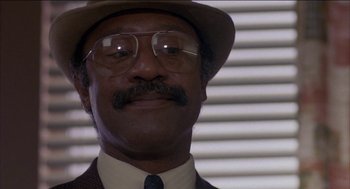 Movie still from “Remo Williams: The Adventure Begins” (1985), directed by Guy Hamilton – A person wearing glasses and a hat; Close Up shot, Low angle