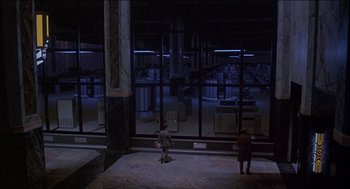 Movie still from “Remo Williams: The Adventure Begins” (1985), directed by Guy Hamilton – Two young children are standing in front of a large window; Extreme Wide shot, High angle