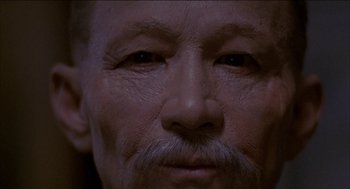 Movie still from “Remo Williams: The Adventure Begins” (1985), directed by Guy Hamilton – An old man with a mustache and a beard; Extreme Close Up shot, High angle