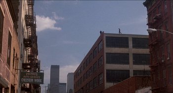 Movie still from “Remo Williams: The Adventure Begins” (1985), directed by Guy Hamilton – A man is standing on the top of a building; Extreme Wide shot, Low angle