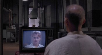Movie still from “Remo Williams: The Adventure Begins” (1985), directed by Guy Hamilton – An older man watching a television in a kitchen; Close Up shot, Over the shoulder angle