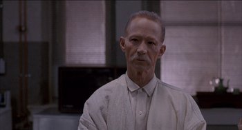 Movie still from “Remo Williams: The Adventure Begins” (1985), directed by Guy Hamilton – An old man with a mustache and a white shirt; Close Up shot, Low angle