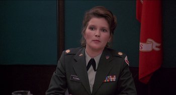 Movie still from “Remo Williams: The Adventure Begins” (1985), directed by Guy Hamilton – A woman in a military uniform sitting in front of a wall; Close Up shot, Low angle