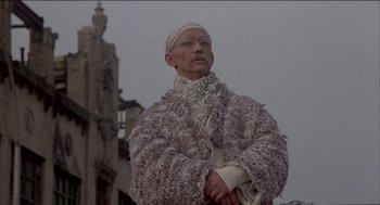 Movie still from “Remo Williams: The Adventure Begins” (1985), directed by Guy Hamilton – An older woman wearing a fur coat and a white turban; Medium shot, Low angle