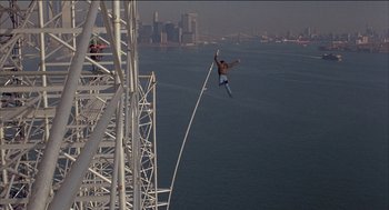 Movie still from “Remo Williams: The Adventure Begins” (1985), directed by Guy Hamilton – A man flying through the air while riding a skateboard over a body of water; Wide shot, High angle