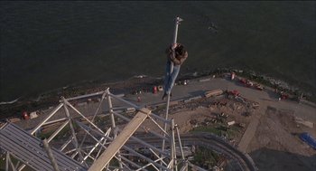 Movie still from “Remo Williams: The Adventure Begins” (1985), directed by Guy Hamilton – A man standing on top of a metal structure; Wide shot, Overhead angle