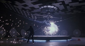 Movie still from “Remo Williams: The Adventure Begins” (1985), directed by Guy Hamilton – A man standing in front of a ceiling fan; Extreme Wide shot, Low angle