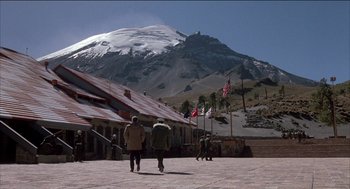 Movie still from “Remo Williams: The Adventure Begins” (1985), directed by Guy Hamilton – Two people walking in front of a snowy mountain; Extreme Wide shot, High angle