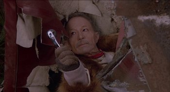 Movie still from “Remo Williams: The Adventure Begins” (1985), directed by Guy Hamilton – An old man is holding a wrench in his hand; Close Up shot, Overhead angle