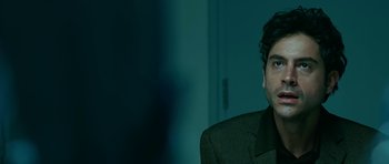 Movie still from “Rendition” (2007), directed by Gavin Hood – A man in a suit is sitting in front of a wall; Close Up shot, Over the shoulder angle