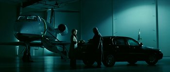 Movie still from “Rendition” (2007), directed by Gavin Hood – Two people in a dark room with a car and a plane in the background; Wide shot, Low angle