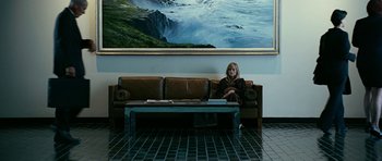 Movie still from “Rendition” (2007), directed by Gavin Hood – A woman sitting on top of a couch in front of a painting on the wall; Wide shot, High angle