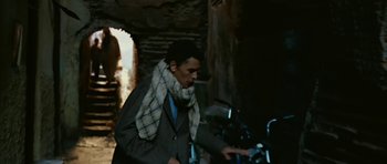Movie still from “Rendition” (2007), directed by Gavin Hood – A man wearing a scarf standing in front of a motorcycle; Medium shot, Low angle