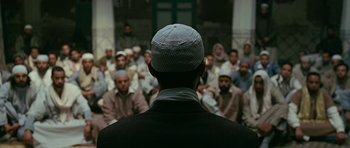 Movie still from “Rendition” (2007), directed by Gavin Hood – A group of men sitting in front of each other in front of a building; Medium shot, Over the shoulder angle