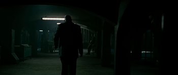 Movie still from “Rendition” (2007), directed by Gavin Hood – A man in a suit walking down a dark hallway; Wide shot, Over the shoulder angle