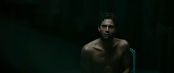 Movie still from “Rendition” (2007), directed by Gavin Hood – A man with no shirt is sitting in a dark room; Close Up shot, Low angle