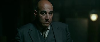 Movie still from “Rendition” (2007), directed by Gavin Hood – A bald man in a suit and tie looking to his left; Close Up shot, Over the shoulder angle