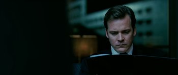 Movie still from “Rendition” (2007), directed by Gavin Hood – A man wearing a suit and tie looking at a book; Close Up shot, Over the shoulder angle