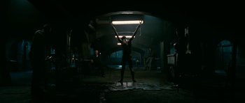 Movie still from “Rendition” (2007), directed by Gavin Hood – A woman standing under a light in a dark room; Wide shot, Low angle