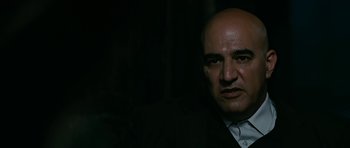 Movie still from “Rendition” (2007), directed by Gavin Hood – A bald man in a black suit and white shirt; Close Up shot, Low angle