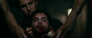 Movie still from “Rendition” (2007), directed by Gavin Hood – A man is holding another man's face with blood on his face; Close Up shot, Low angle