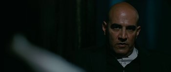 Movie still from “Rendition” (2007), directed by Gavin Hood – A bald man in a suit and tie looking at the camera; Close Up shot, Over the shoulder angle