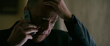 Movie still from “Rendition” (2007), directed by Gavin Hood – An older man is talking on a cell phone while holding his hand up to his head; Close Up shot, High angle