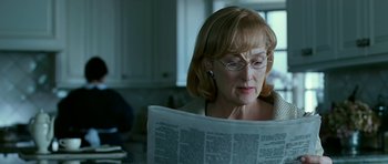 Movie still from “Rendition” (2007), directed by Gavin Hood – A woman reading a newspaper while wearing glasses; Close Up shot, Over the shoulder angle
