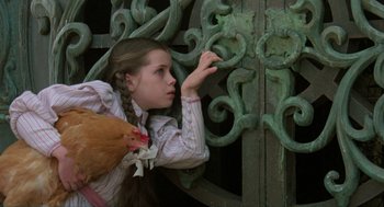 Movie still from “Return to Oz” (1985), directed by Walter Murch – A young girl holding a chicken near an iron gate; Close Up shot, High angle