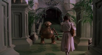 Movie still from “Return to Oz” (1985), directed by Walter Murch – A woman standing in front of a robot statue in a room; Wide shot, Low angle