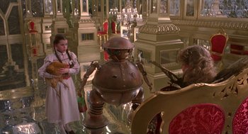 Movie still from “Return to Oz” (1985), directed by Walter Murch – A woman and a girl standing in front of a robot statue; Wide shot, High angle