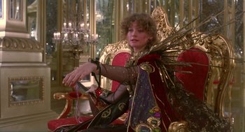 Movie still from “Return to Oz” (1985), directed by Walter Murch – A woman sitting on a red chair holding a glass; Medium shot, Low angle