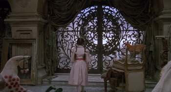 Movie still from “Return to Oz” (1985), directed by Walter Murch – A young girl in a pink dress looking out of an iron gate; Wide shot, High angle
