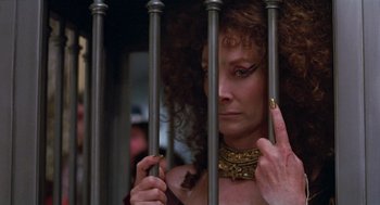 Movie still from “Return to Oz” (1985), directed by Walter Murch – A woman in a gold necklace is behind a metal fence; Close Up shot, Low angle