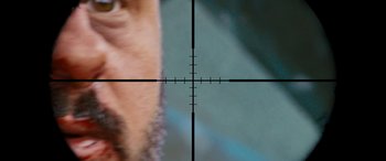 Movie still from “Revenge” (2017), directed by Coralie Fargeat – A man's face with a rifle sight in the background; Extreme Close Up shot, Overhead angle